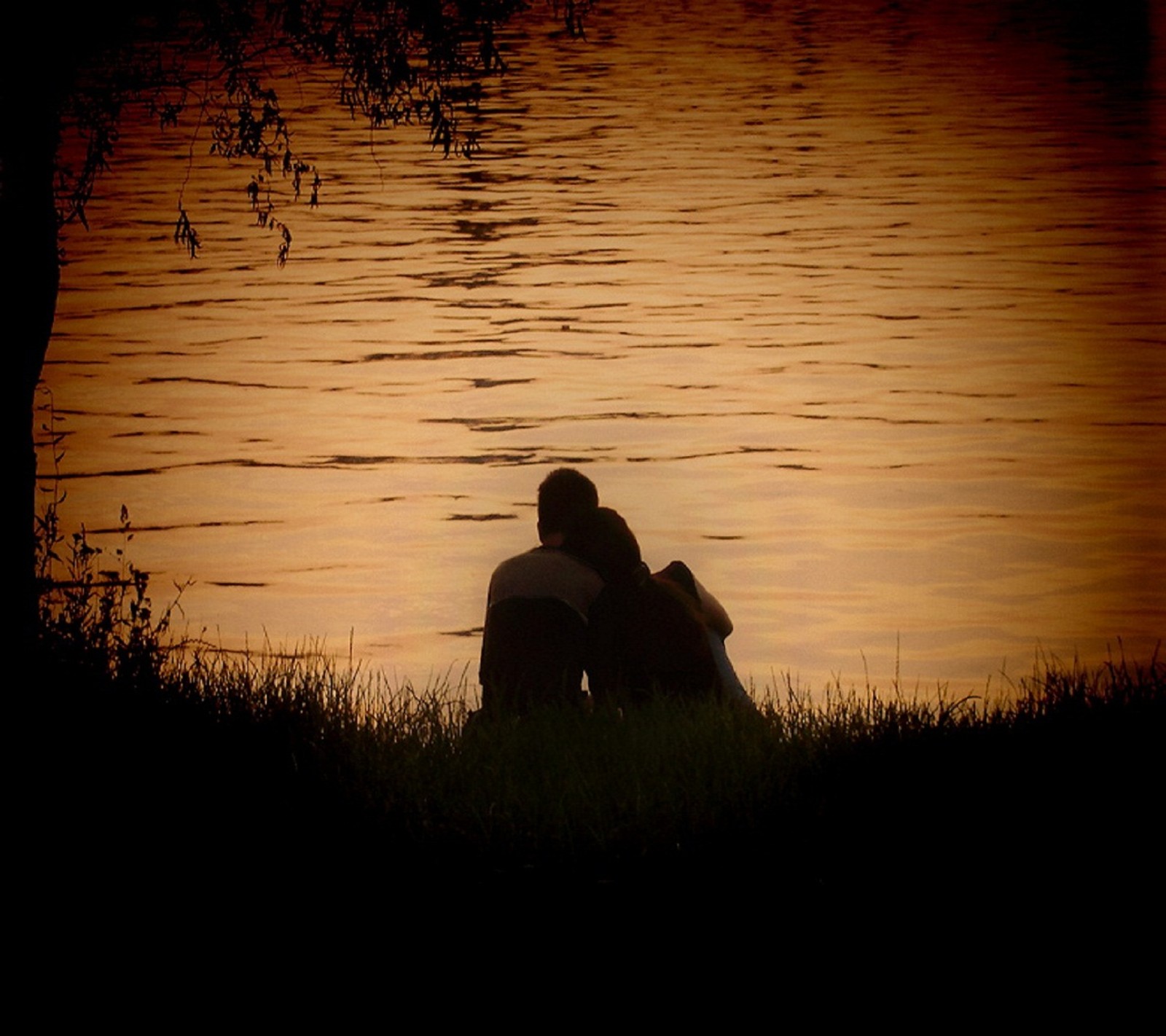 Deux personnes assises dans l'herbe près de l'eau (tomber amoureux, cœur, vie)