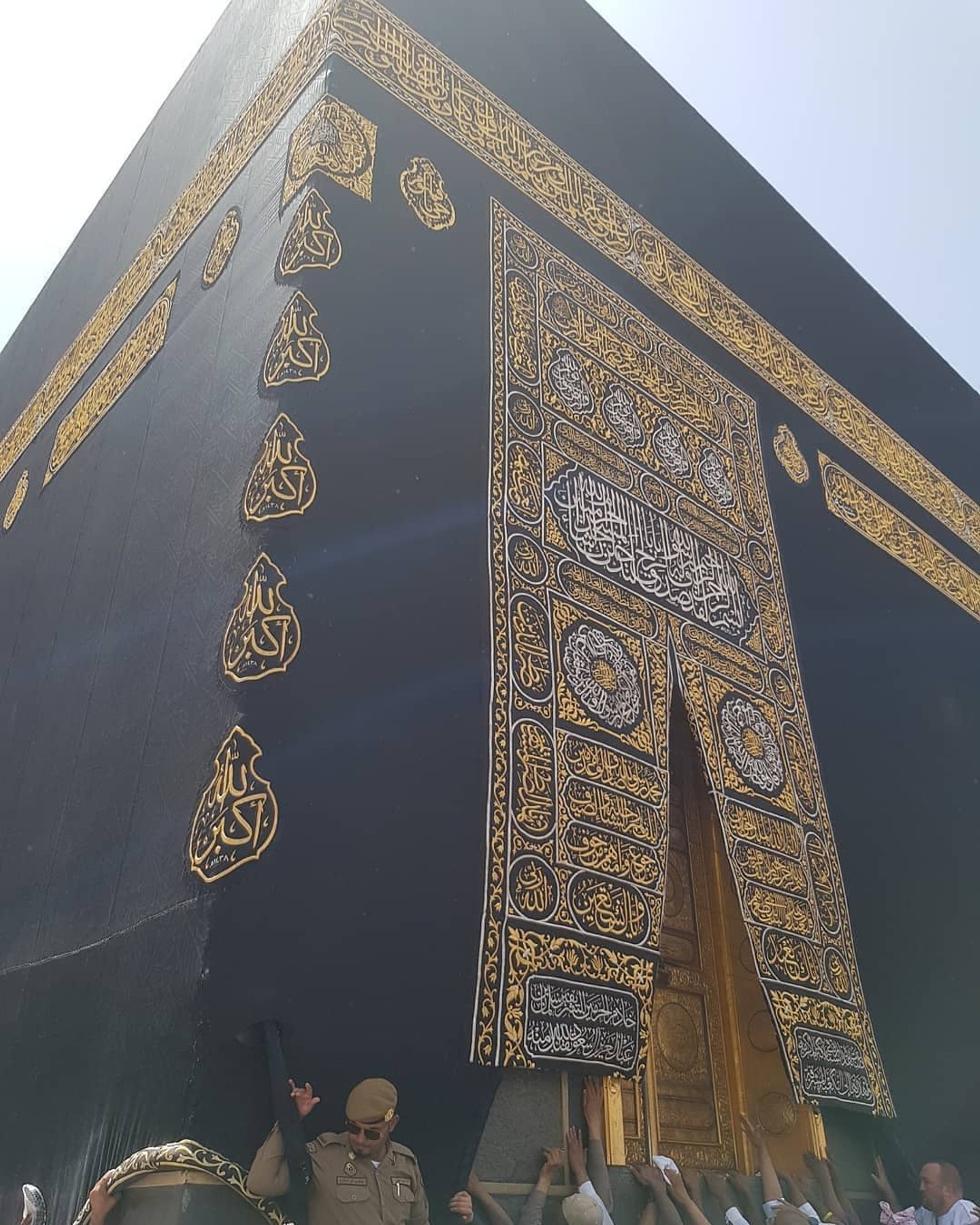 Menschen stehen um ein großes schwarzes gebäude mit goldenen mustern (allah, islam, kaaba, madina, muslim)