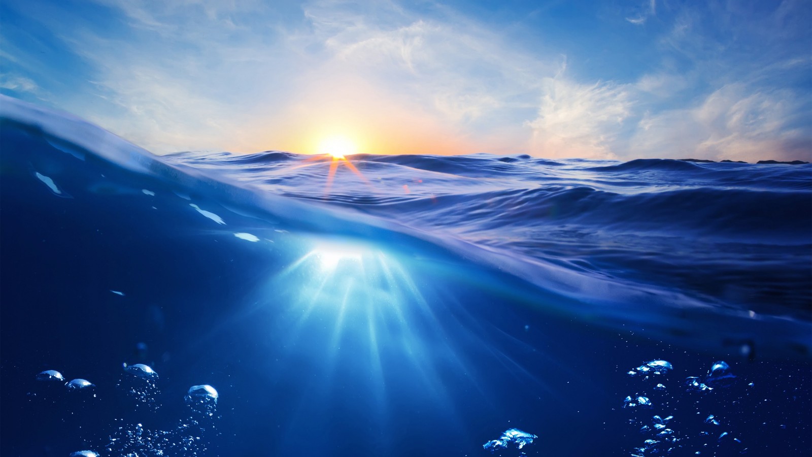 A view of the sun shining through the water with bubbles (water, ocean, sea, sunlight, wave)