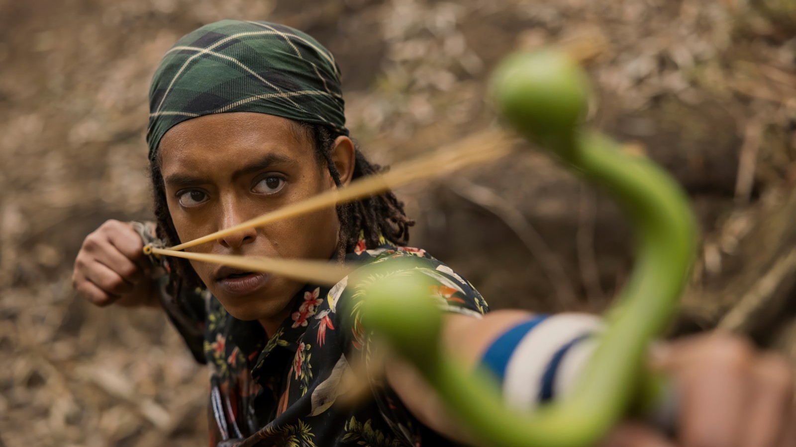 Hay un hombre con una serpiente verde en la cabeza sosteniendo un arco (usopp, one piece, acción en vivo, series de televisión, netflix)