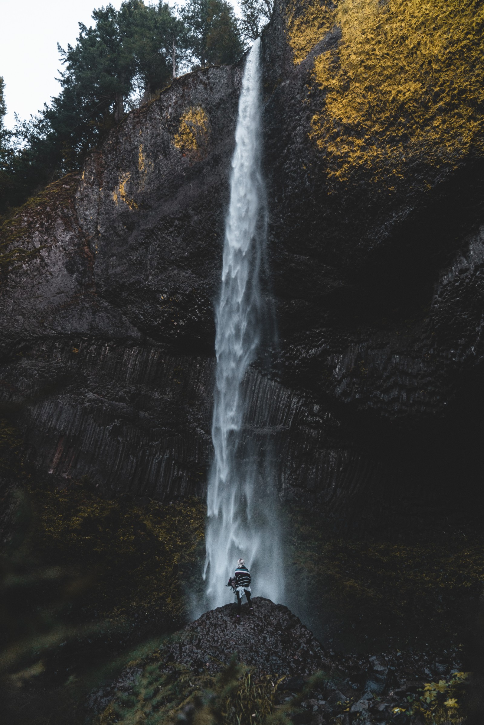 Il y a un homme debout devant une cascade avec un sac à dos (la cascade, eau, nature, ressources en eau, paysage naturel)