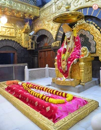 Idole de Shirdi Sai Baba entouré d'offrandes florales dans un cadre de temple doré