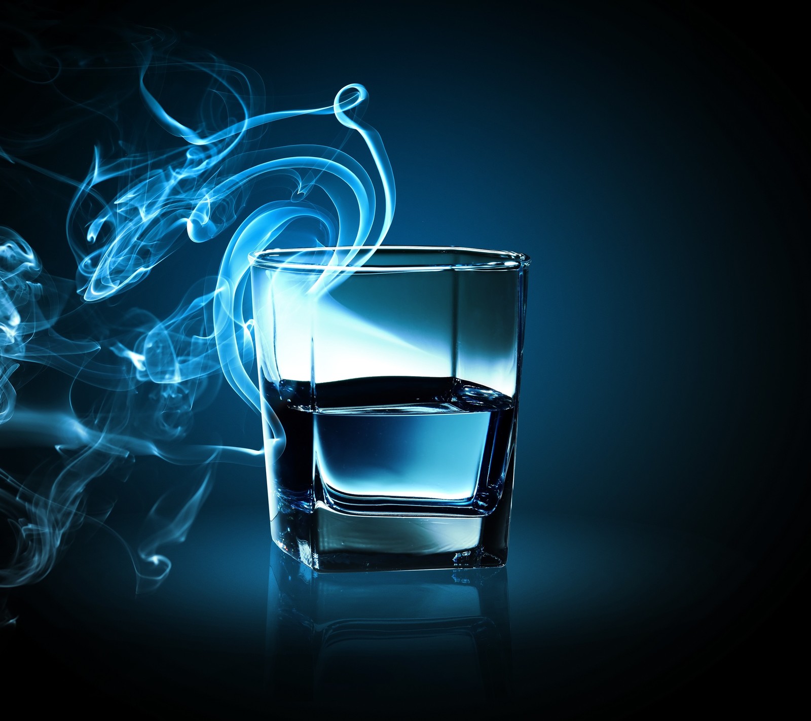 El humo se eleva de un vaso de agua con un fondo azul (bebida, vidrio, humo, vapor)