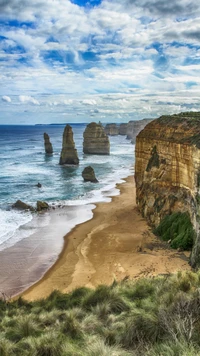 Falaises côtières majestueuses et formations rocheuses emblématiques le long d'une plage sereine sous un ciel dramatique.