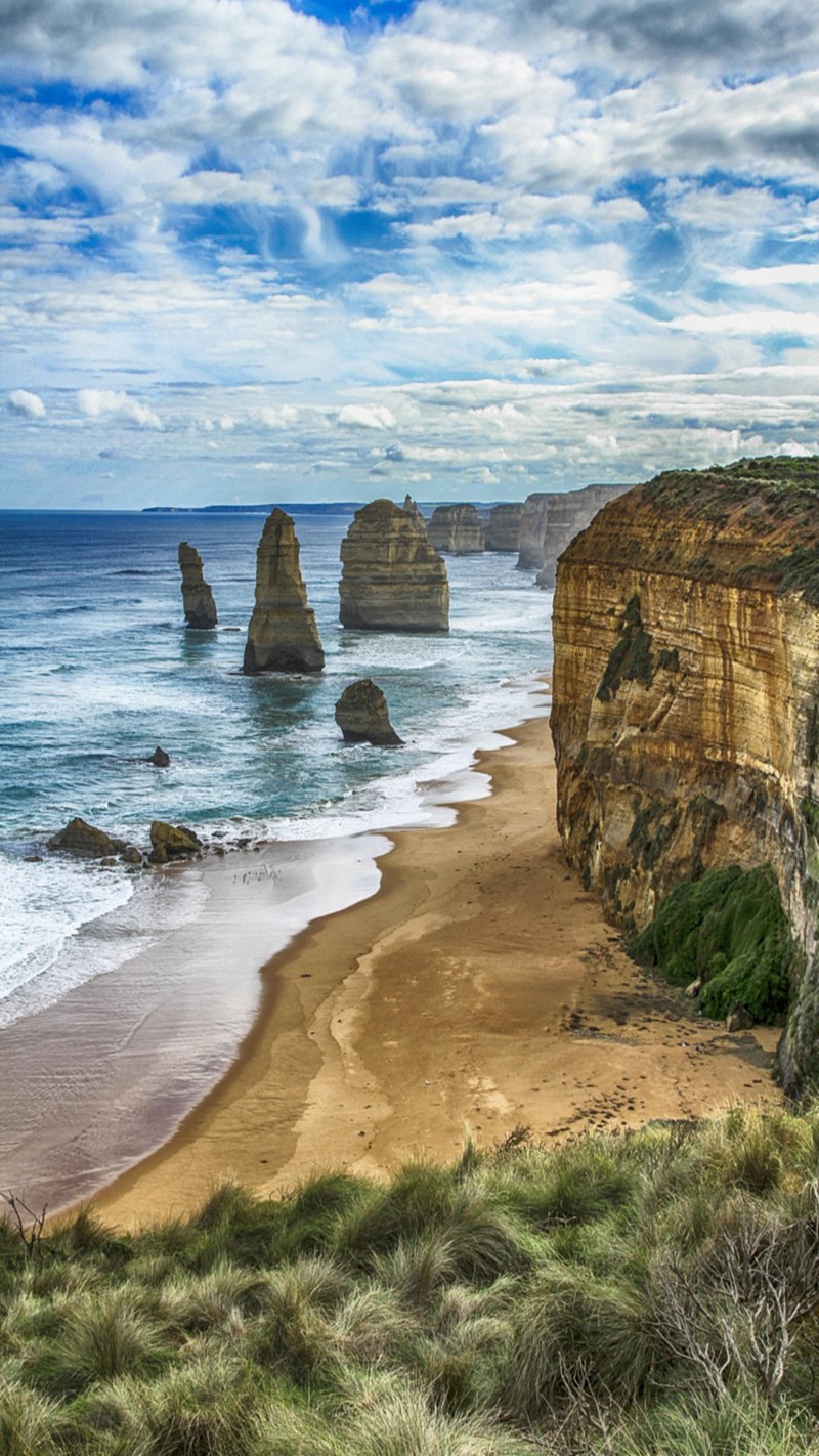 There is a view of a beach with a few cliffs in the background (landscape, nature)