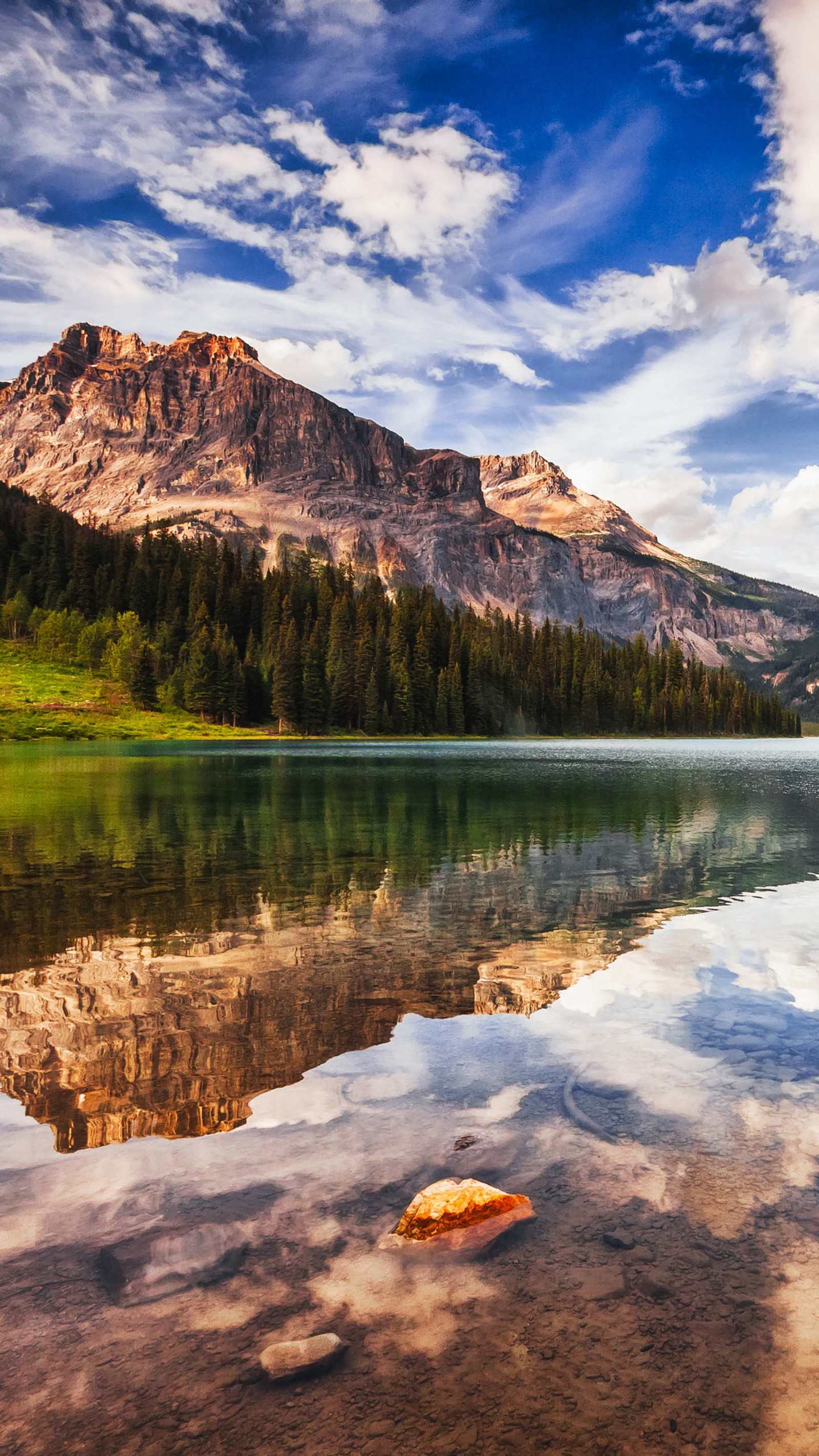 Montanhas refletidas na água de um lago com uma rocha em primeiro plano (lago, natureza)