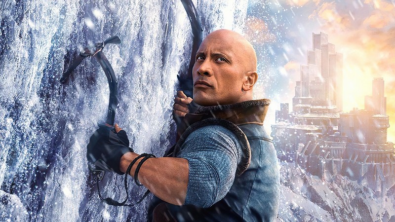 A man in a blue shirt and black gloves holding a bow (dwayne johnson, hairstyle, daytime, world, human)