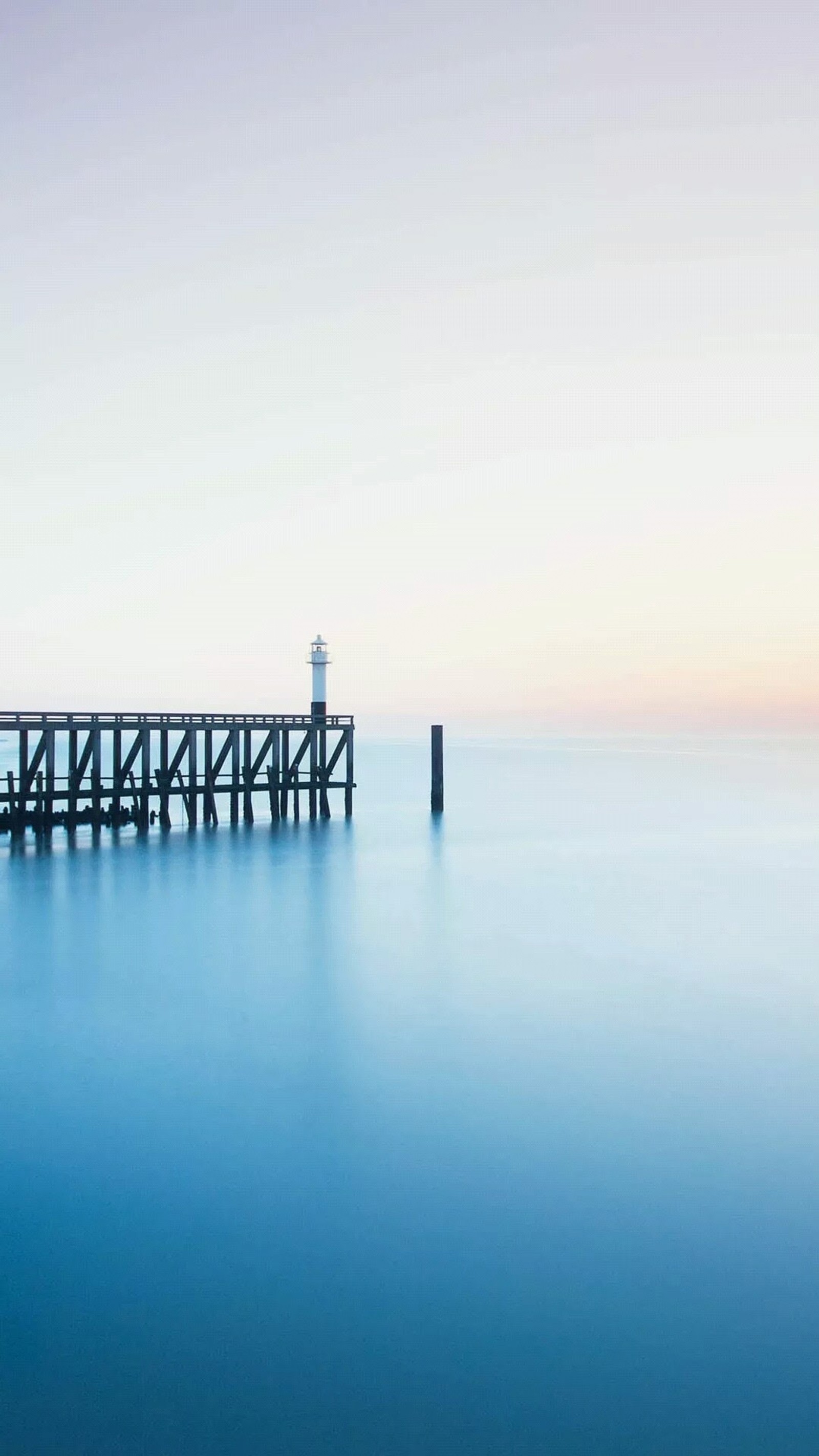 Un muelle en medio de un océano tranquilo con un faro a lo lejos (umidigi, umidigi crystal, cuerpo de agua, azul, fluido)