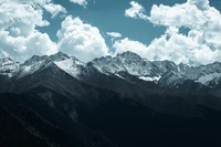 Alpes majestueux enneigés sous des nuages cumulus dramatiques