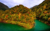 Herbstfarben, die sich im Reservoir spiegeln, umgeben von üppigen Bergen