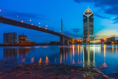 Paisagem urbana vibrante ao crepúsculo: reflexo de arranha-céus e ponte em águas serenas