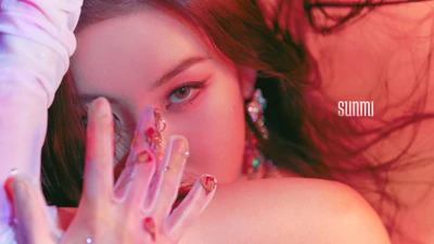 Sunmi en una toma cercana vibrante, mostrando un maquillaje impactante y arte de uñas intrincado contra un fondo colorido.