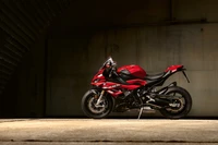 2023 BMW S 1000 RR en un llamativo acabado rojo, exhibida en una iluminación dramática contra un fondo elegante.