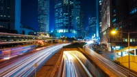 Paisaje urbano vibrante nocturno con rascacielos y estelas de luz en un área metropolitana