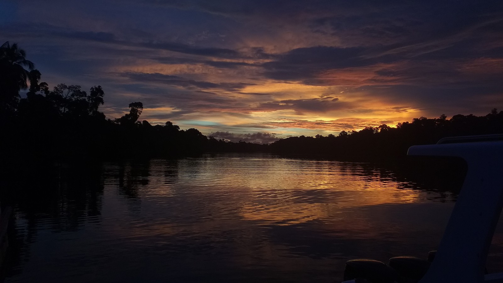 Une vue d'un coucher de soleil sur un plan d'eau avec des arbres en arrière-plan (réflexion, nuage, eau, atmosphère, crépuscule)