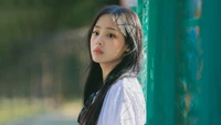 Minji from NewJeans in a serene moment, exuding youthful charm and introspection.