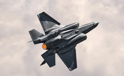 F-35 Lightning II in flight against a cloudy sky.