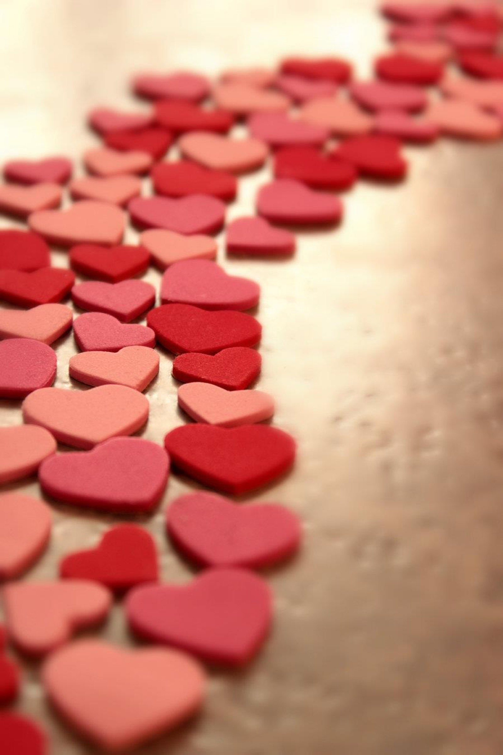 Hearts scattered on a table with a red and pink background (hearts, love, path)