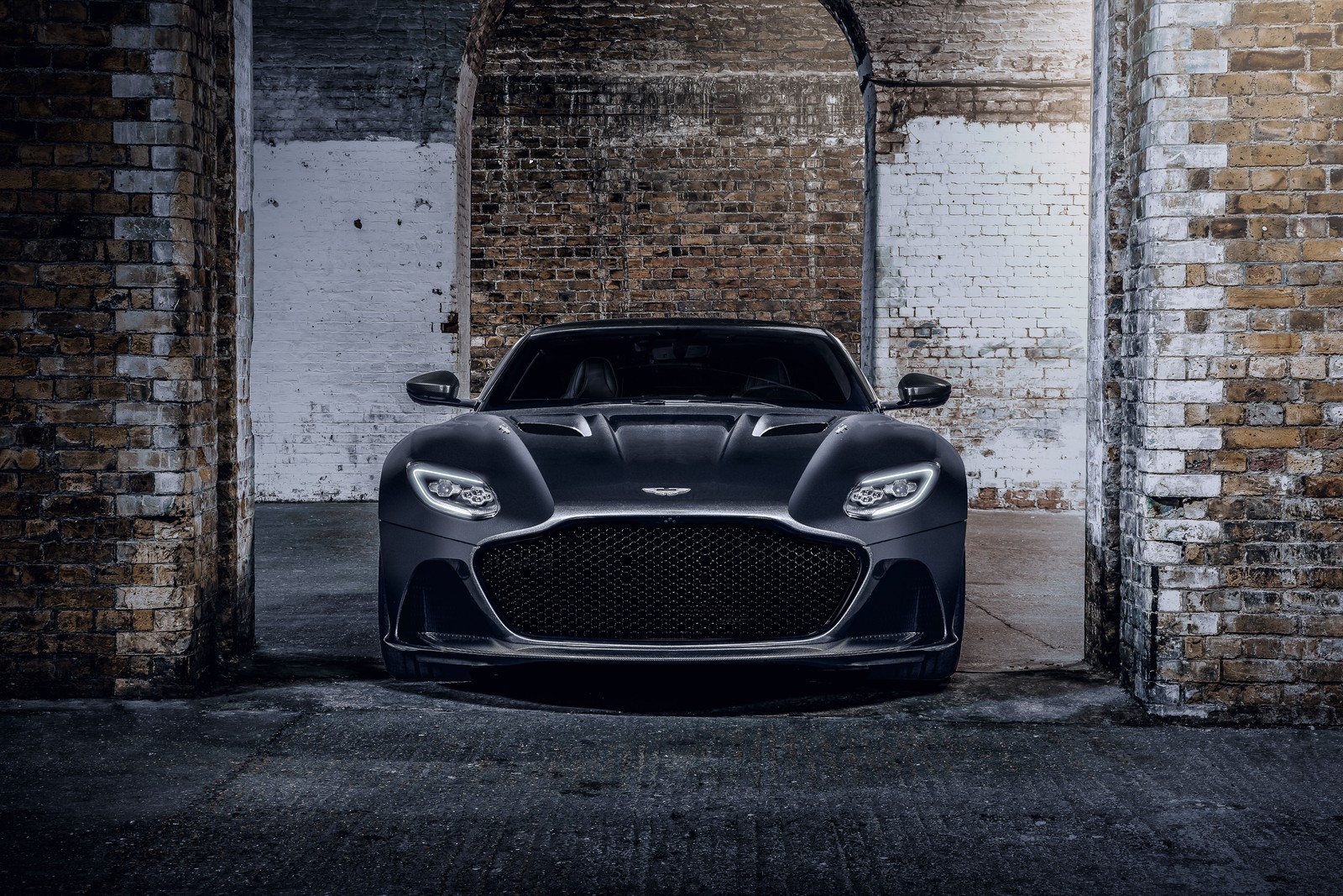 Черный автомобиль aston припаркован перед кирпичной стеной (aston martin dbs superleggera, издание 007, 2020, 5k, машины)