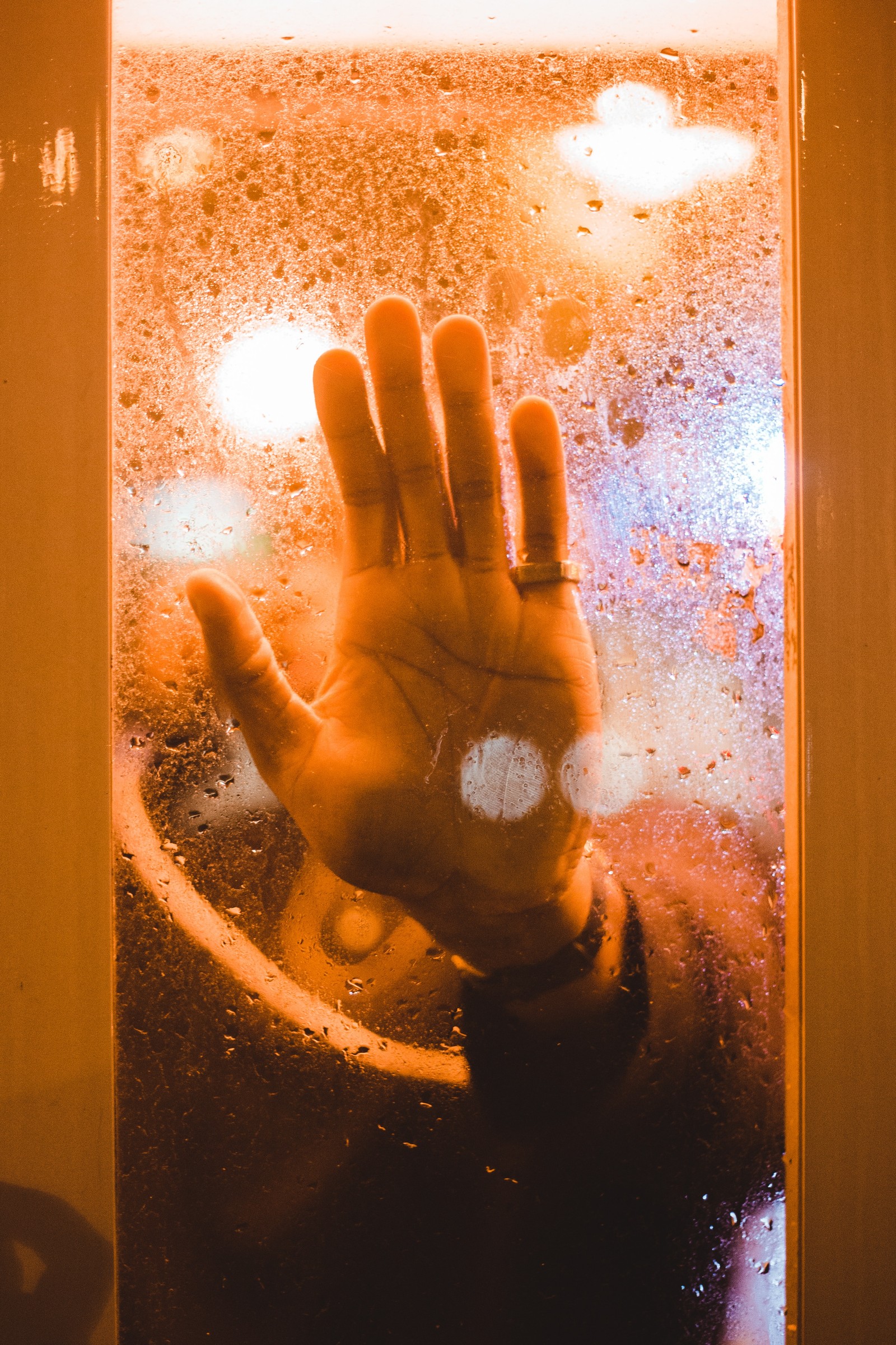 Alguien está levantando la mano frente a una ventana (mano, naranja, ligero, amarillo, agua)