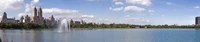 Panoramic View of a City Skyline Reflected in a Serene Reservoir Under a Bright Daytime Sky