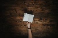 Open Notebook on Hardwood Floor Under Warm Lighting