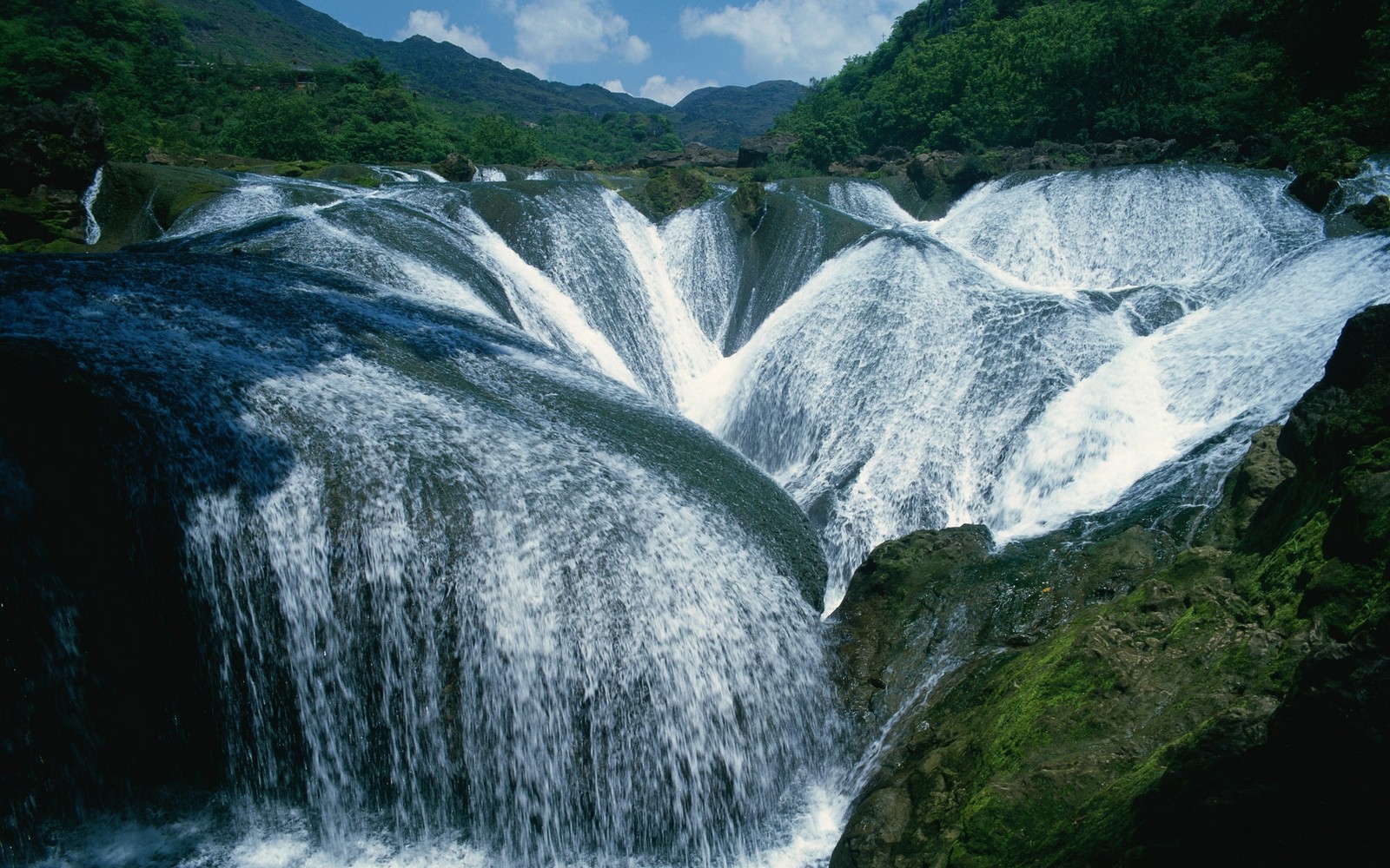 Ein wasserfall, der über einen stein fließt (wasserressourcen, gewässer, natur, wasser, wasserlauf)