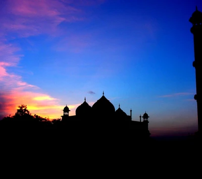 Silhouette d'un monument islamique contre un ciel crépusculaire vibrant.