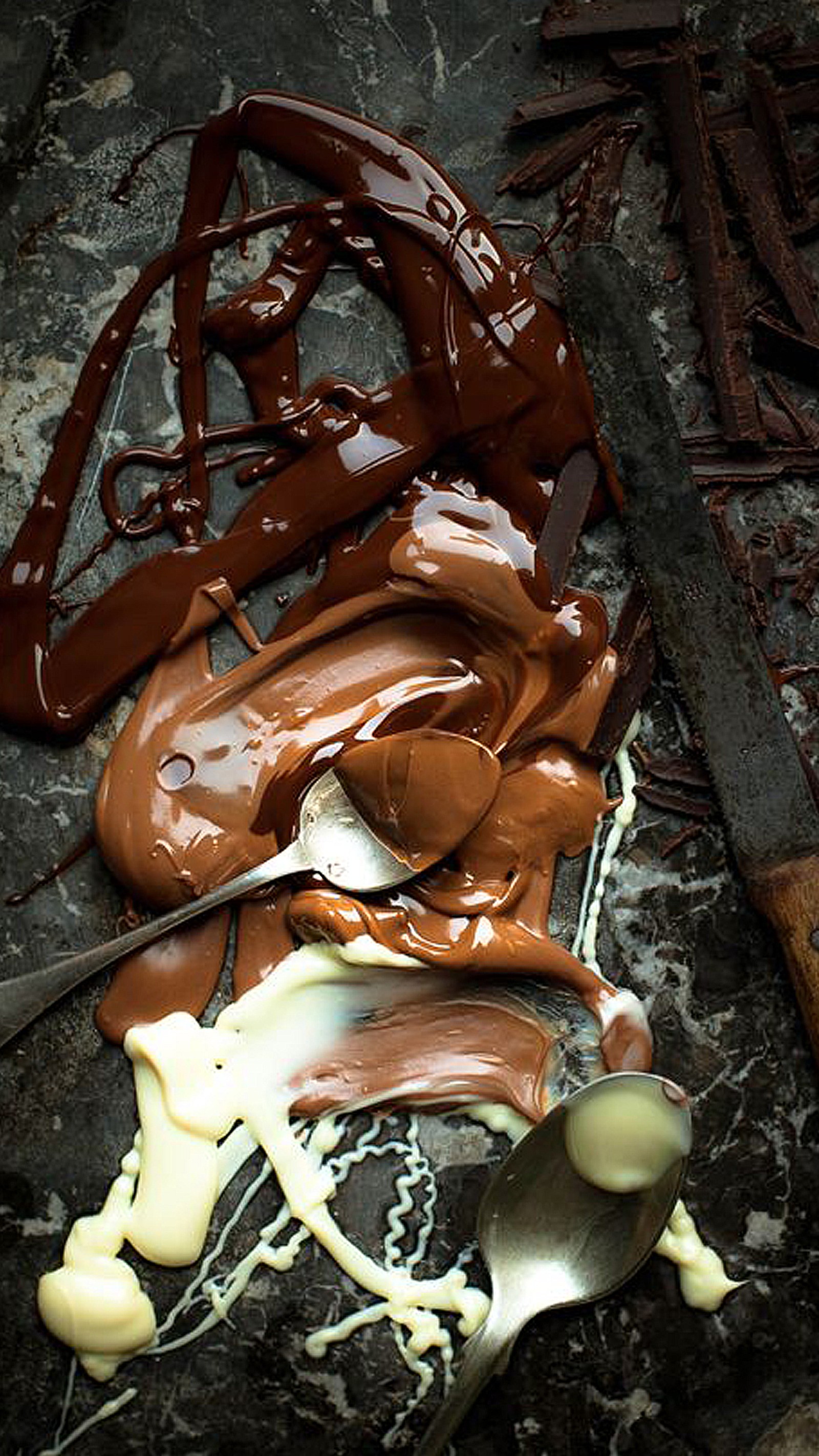 El chocolate se ha derretido y está sobre una mesa con una cuchara (negro, chocolate, comida, blanco)