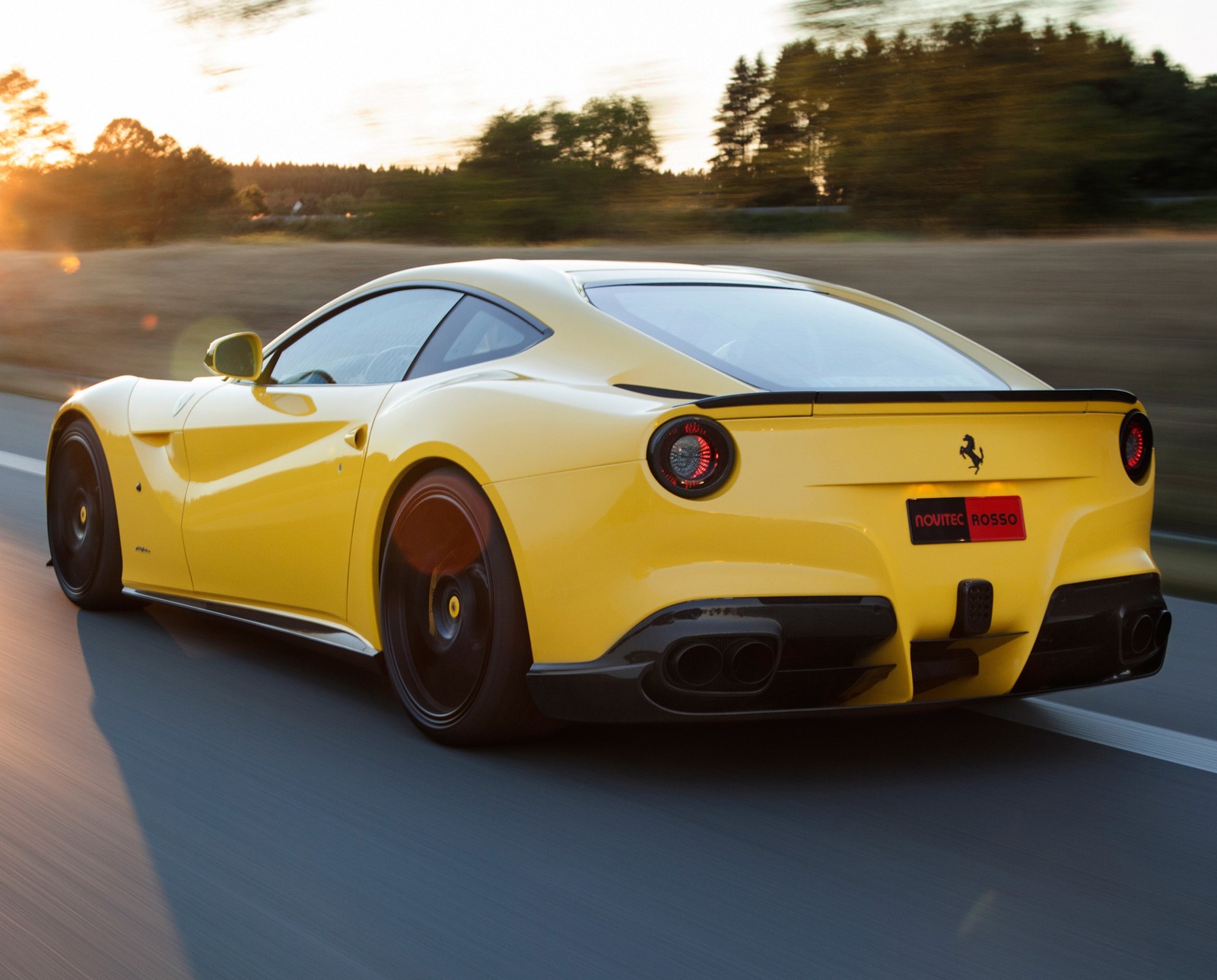 Un coche deportivo ferrari amarillo conduciendo por una carretera al atardecer (coche, coches, f12, rápido, velocidad)