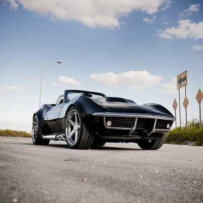 Classic sports car on an open road under a clear sky.