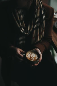 Main élégante tenant une tasse de latte dans une lumière tamisée