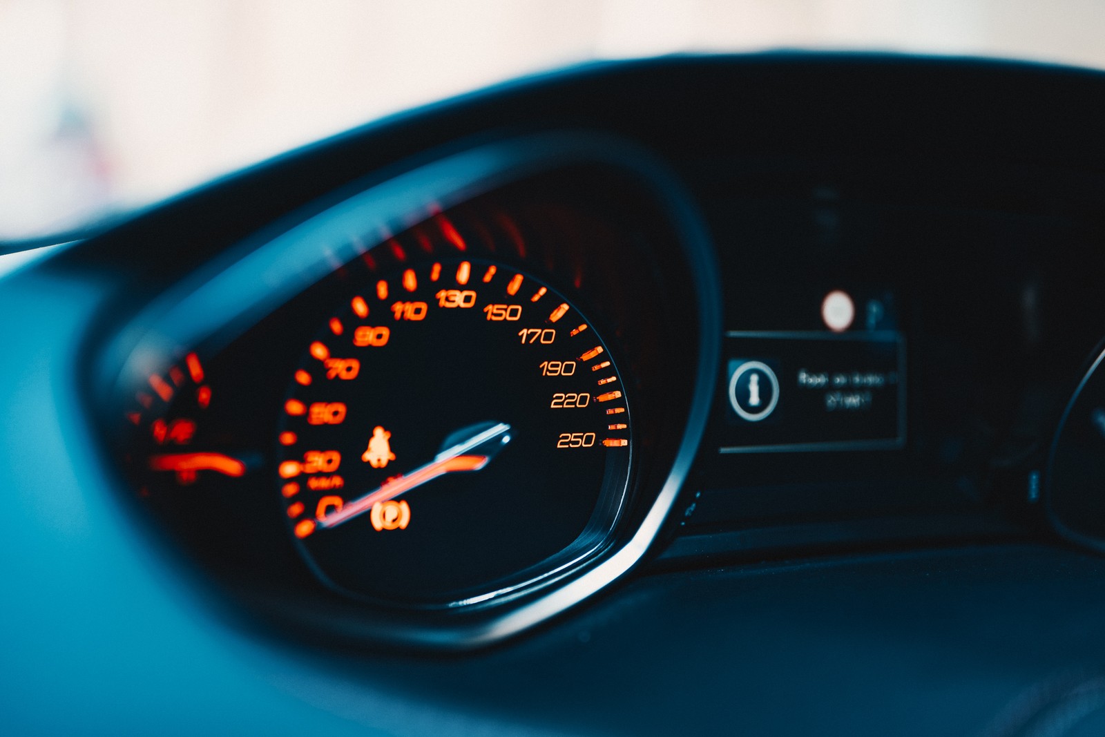 A close up of a car dashboard with a speedometer and a dash light (speedometer, car, measuring instrument, auto part, tachometer)