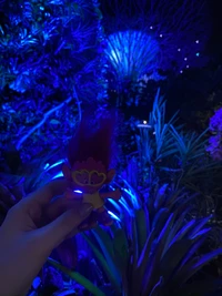 Una figura caprichosa sostiene un vibrante fondo azul eléctrico inspirado en corales, iluminado por una luz encantadora que evoca una sensación de exploración submarina en un entorno de Singapur.