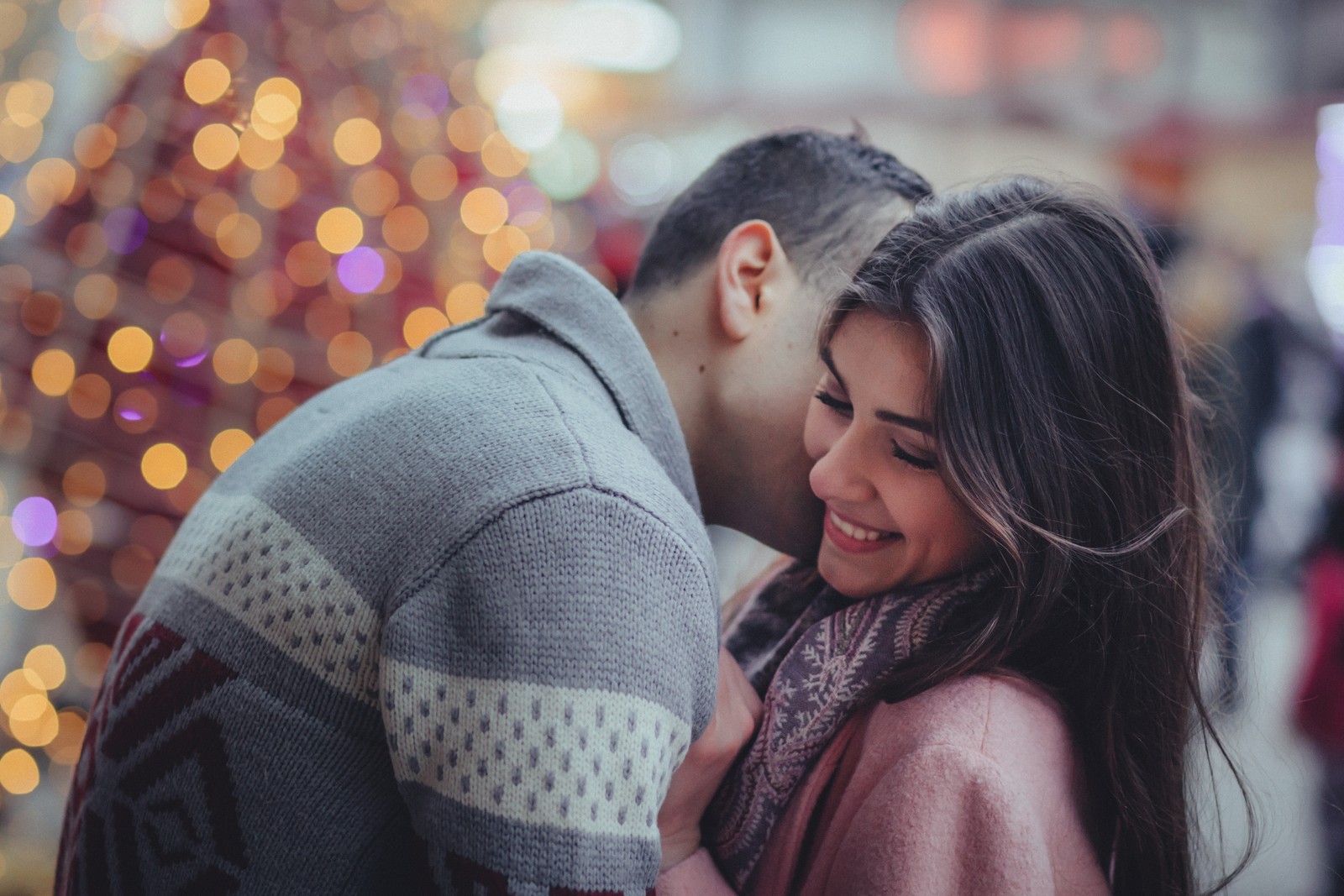 Une femme et un homme s'enlaçant devant un sapin de noël (romance, amour, interaction, baiser, câlin)