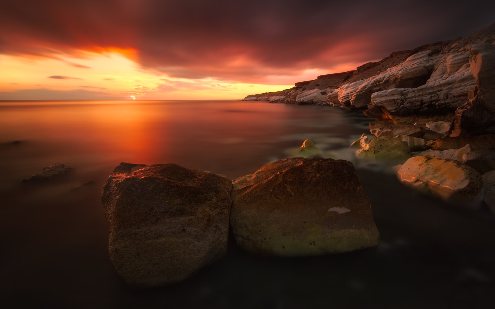 A view of a rocky beach with rocks and a sunset (rocky coast, sunset, seascape, body of water, cliff)