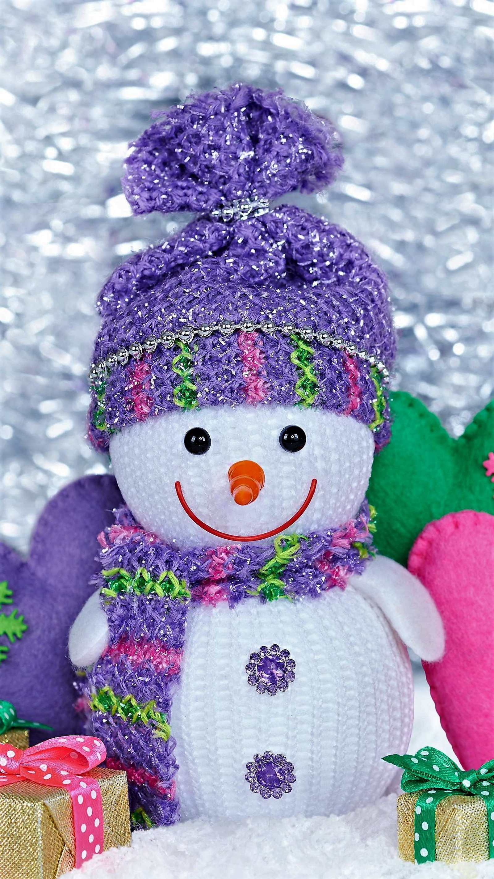 There is a snowman with a purple hat and scarf next to presents (smile, snowman)