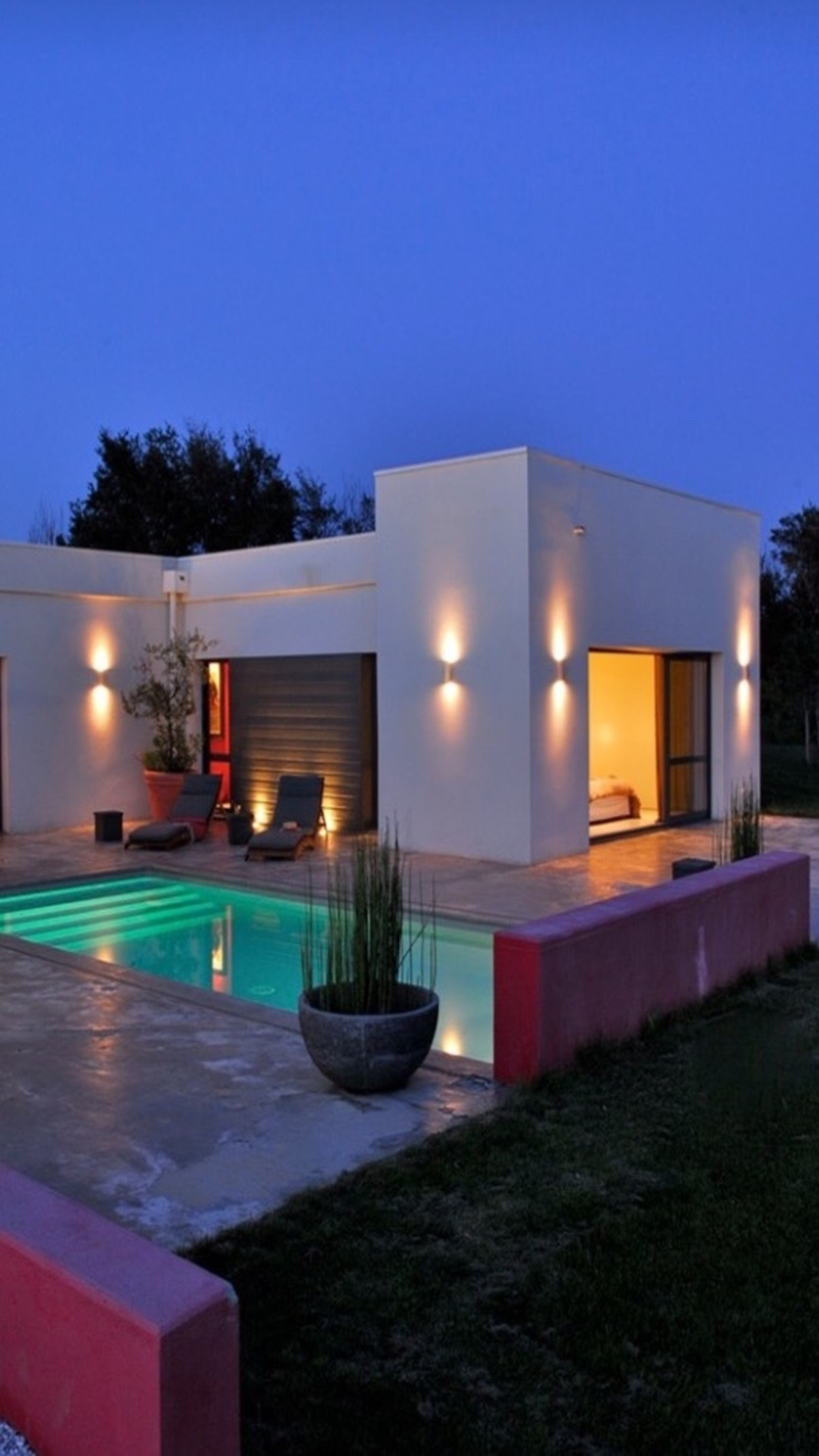 Nighttime view of a modern home with a pool and patio (night, romantic)