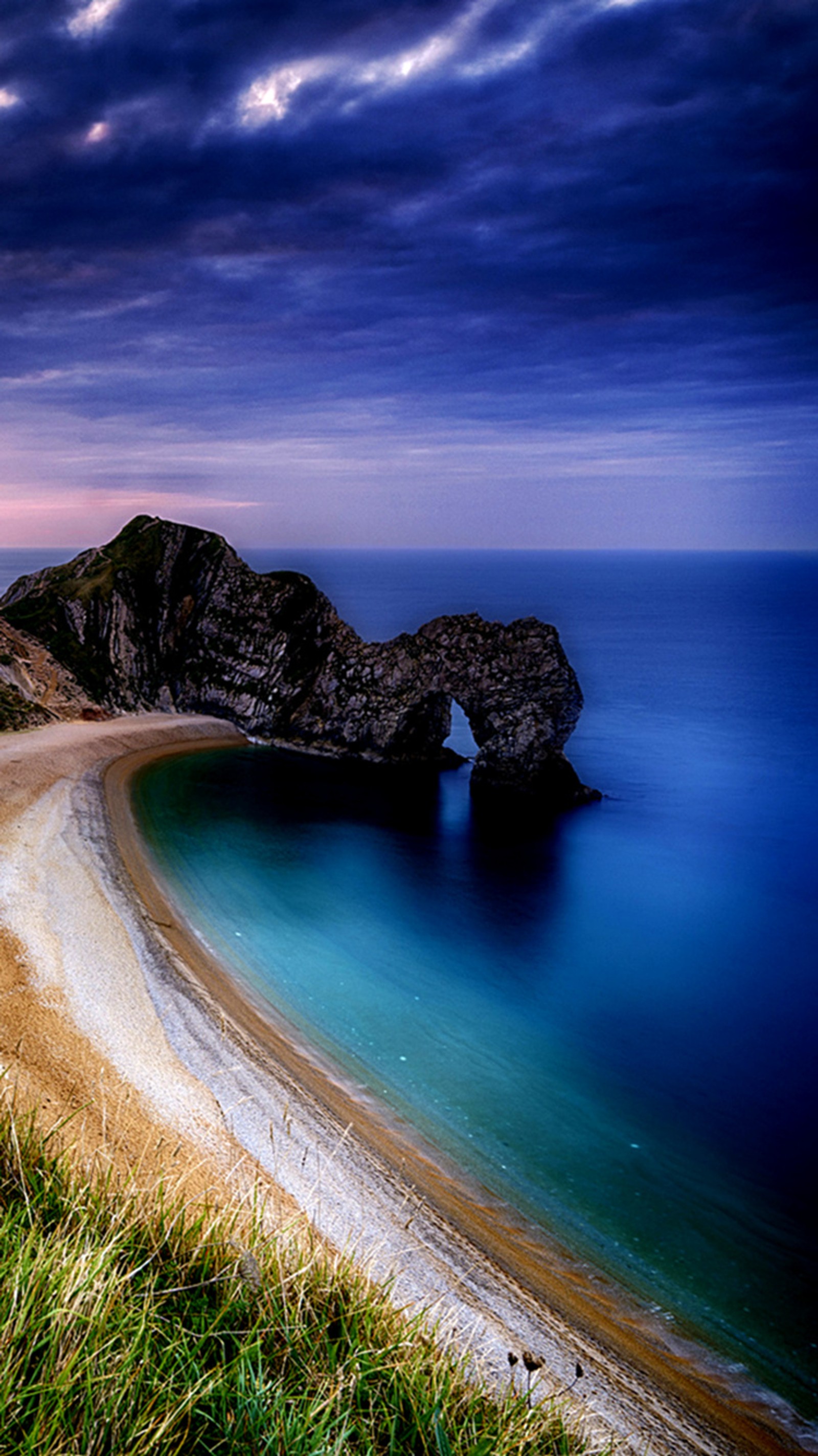 There is a beach with a rock formation in the water (beach, blue, breathtaking, island, paradise)