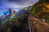 Paisagem urbana noturna com trilho elevado e vista da montanha