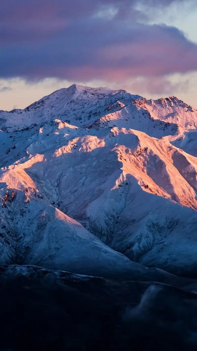 Montagne majestueuse couverte de neige baignée dans la lumière du crépuscule