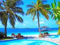 Paraíso tropical: resort frente a la playa con piscina y palmeras.