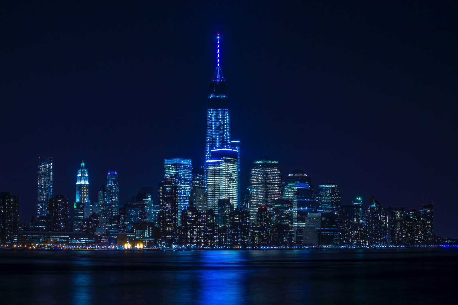 Vista aérea de uma cidade à noite com uma luz azul brilhante (nova york, new york city, silhueta da cidade, paisagem urbana, luzes da cidade)