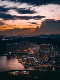 Cityscape at Dusk: Skyscrapers Reflecting Afterglow Over Water and Mountains