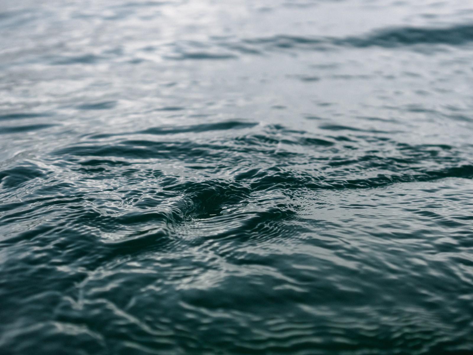 A close up of a body of water with a wave coming in (water, sea, ocean, blue, wave)