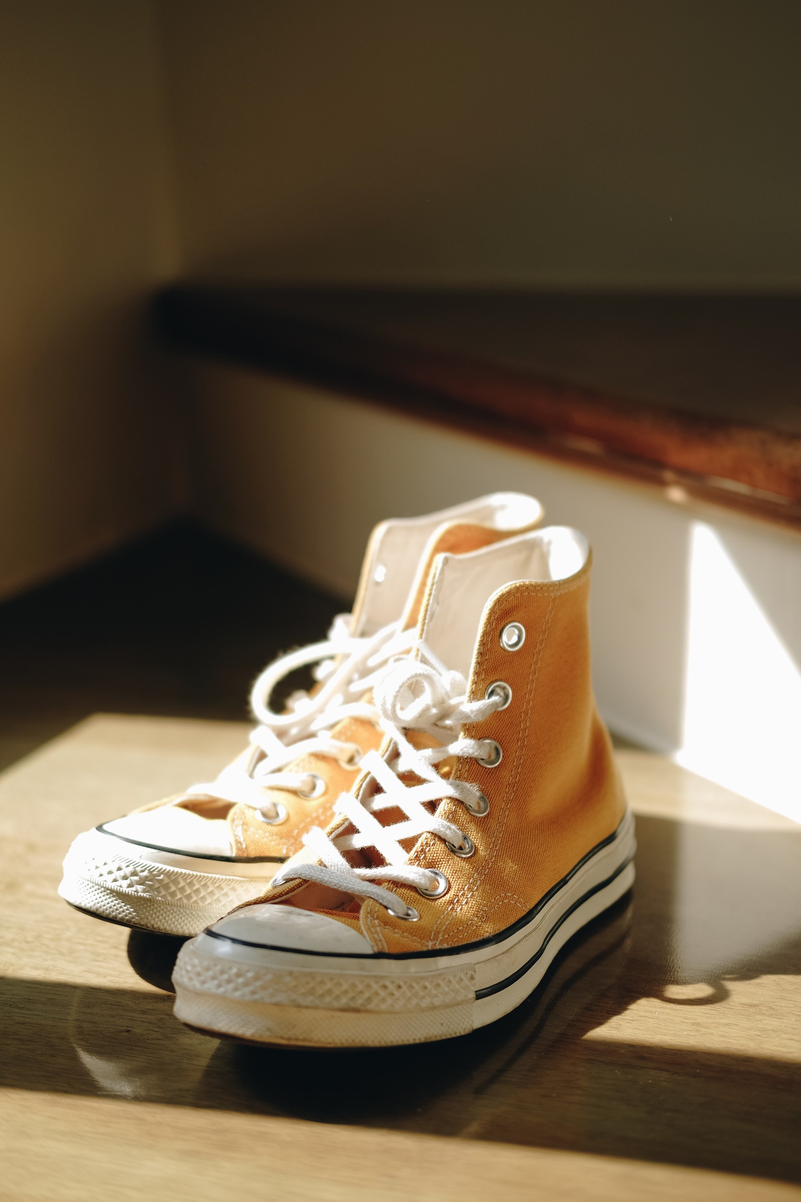 Un par de zapatillas naranjas sentadas sobre un piso de madera (zapatos de skate, converse, zapatilla, marrón, calzado)