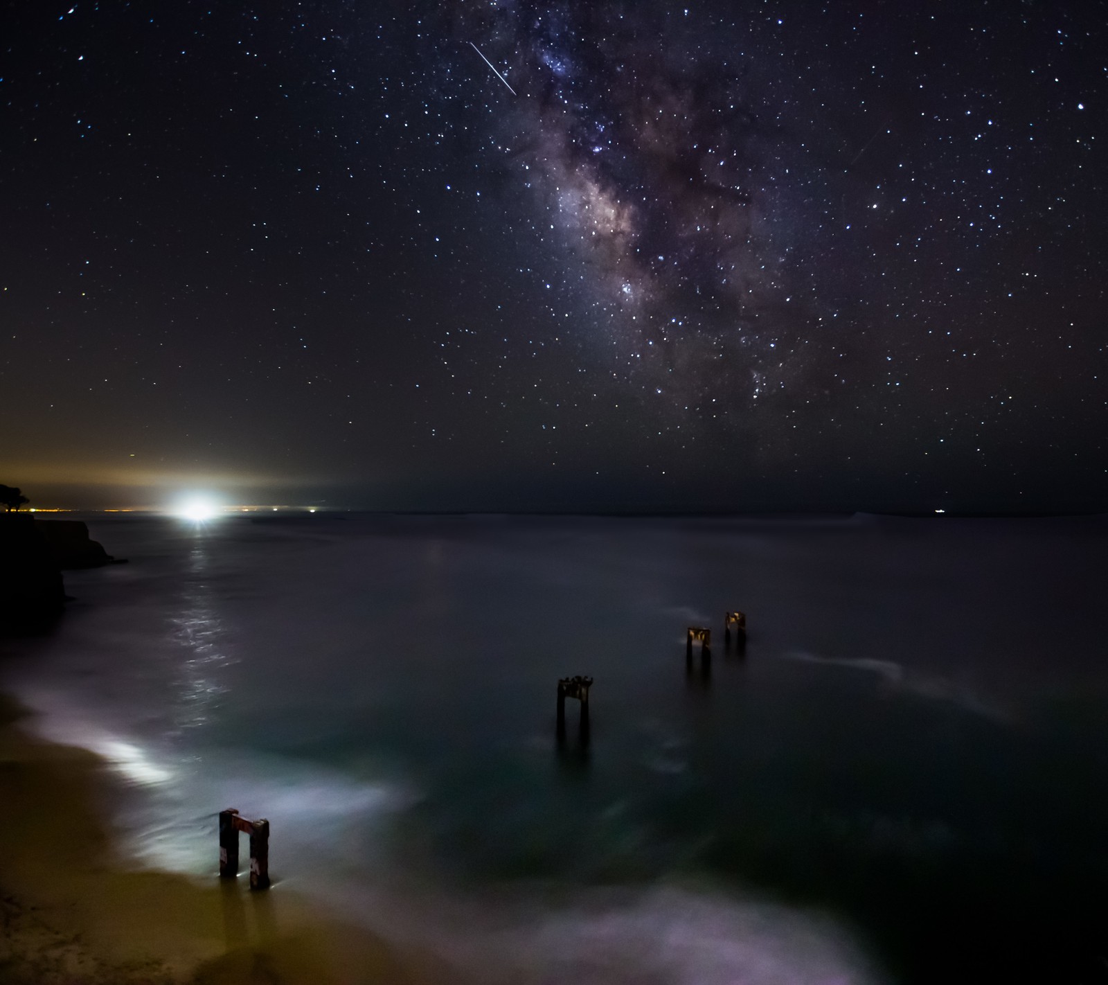 Cielo nocturno con estrellas y vía láctea sobre el océano y el muelle (playa, noche, océano, mar, agua)