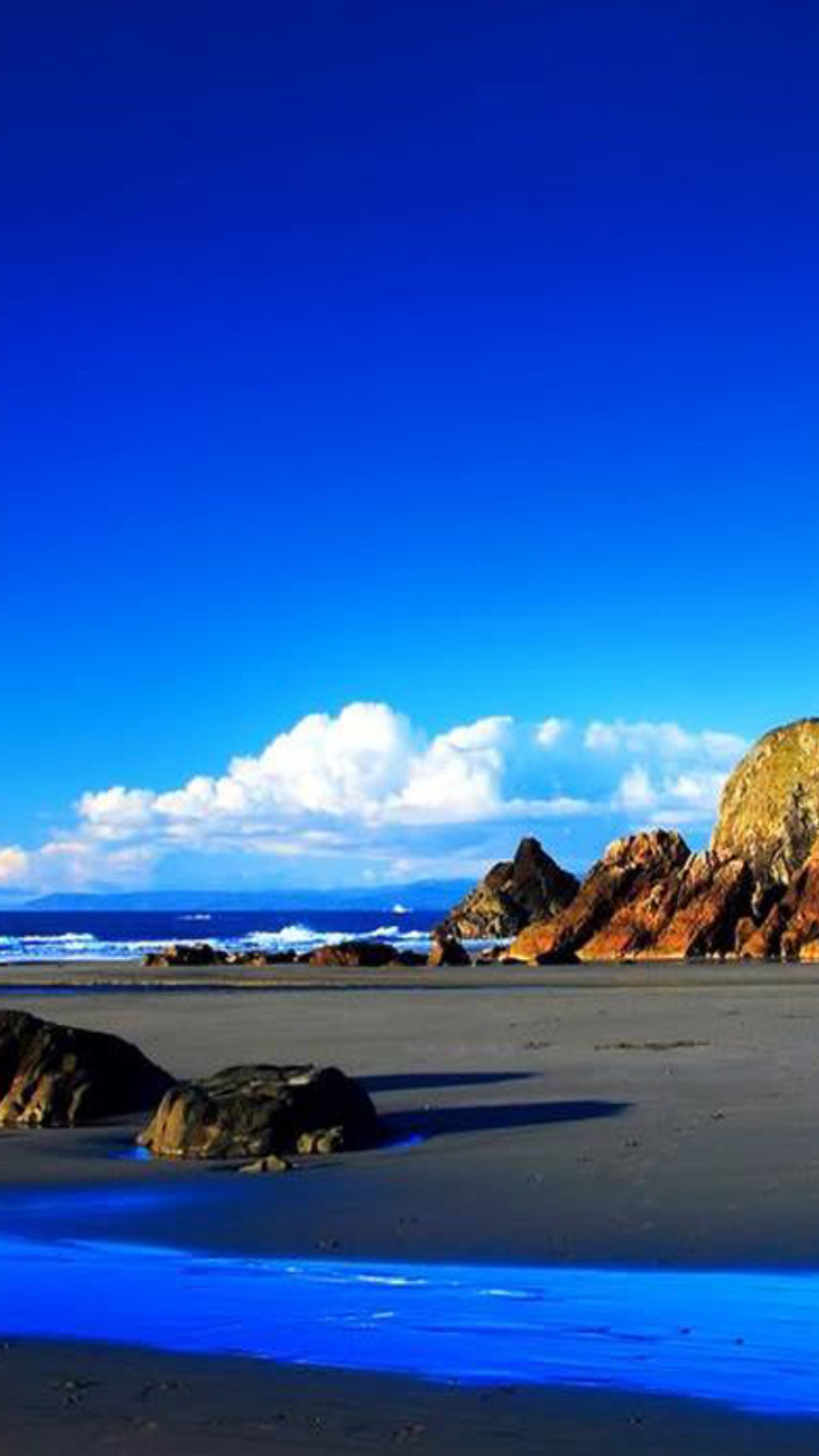 Formação rochosa abstrata na praia com água azul e pedras (azul, natureza)