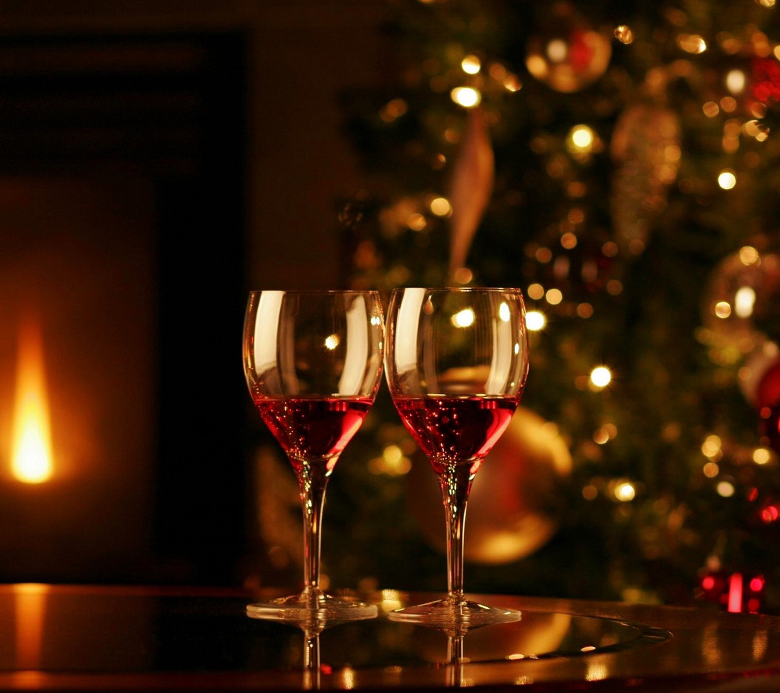 Il y a deux verres à vin sur une table près d'un sapin de noël. (noël, heureux, joyeux, nouveau, année)