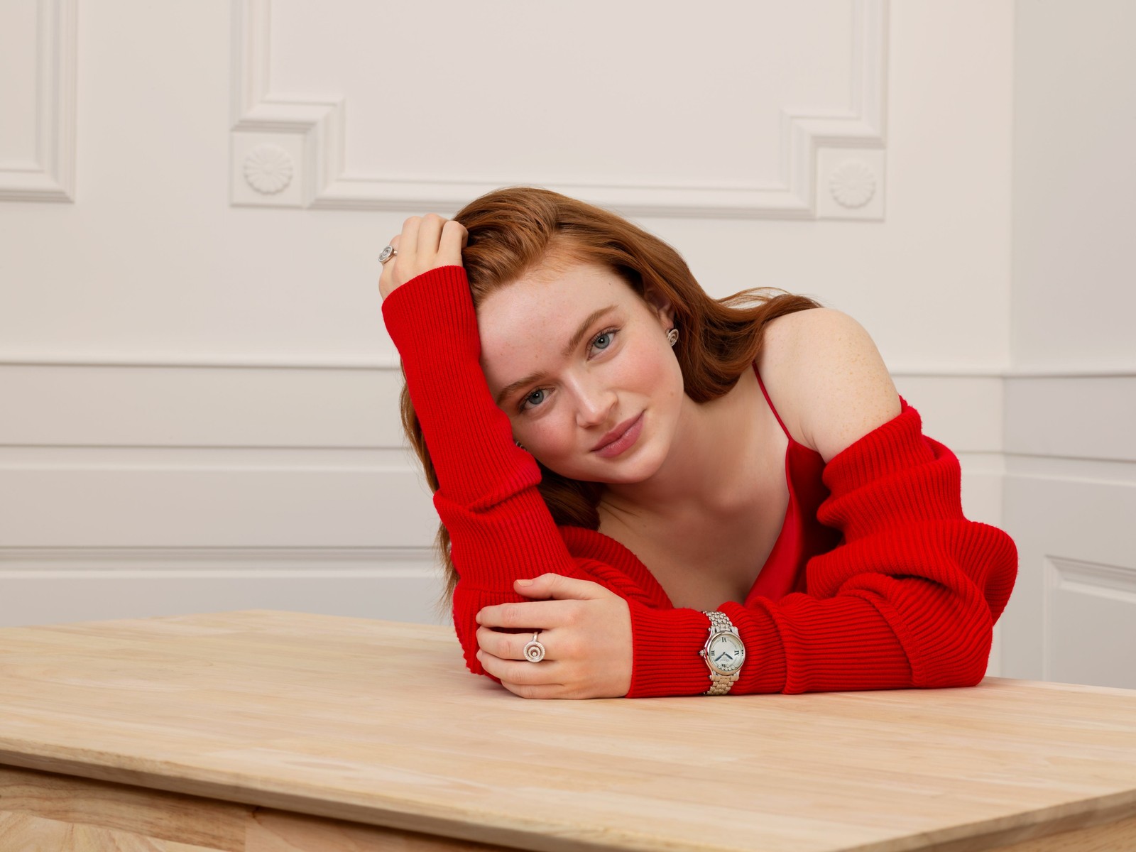 Hay una mujer que está sentada en una mesa con los brazos sobre la cabeza (sadie sink, actriz estadounidense, gente, fondo de pantalla 4k)